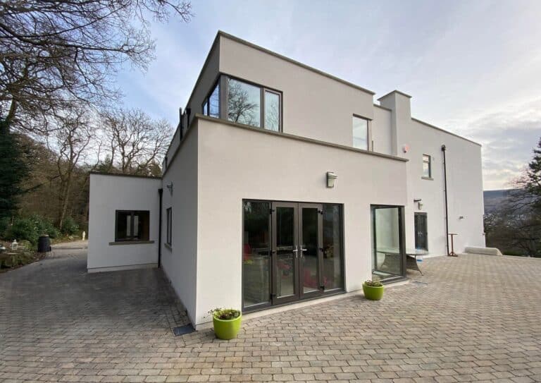 A large, white rendered modern house with large windows.