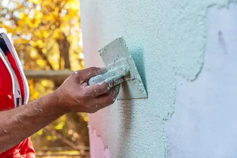 Person applying textured thin coat render to a wall
