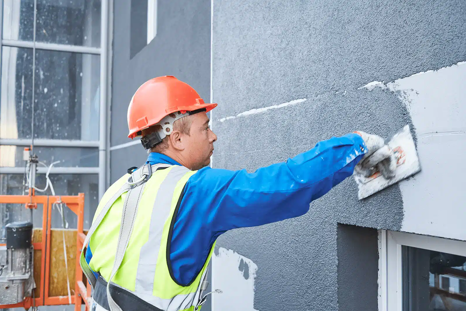 A professional renderer applying thin coat render to a wall