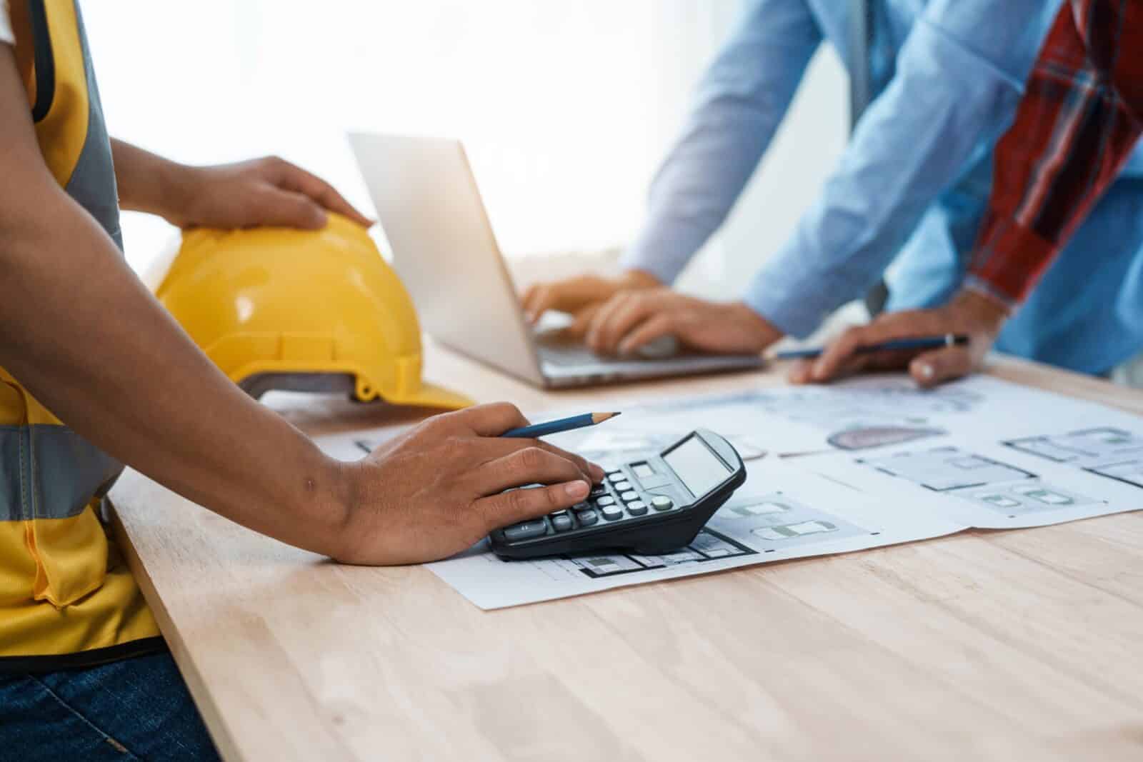Contractors using a calculator on a desk