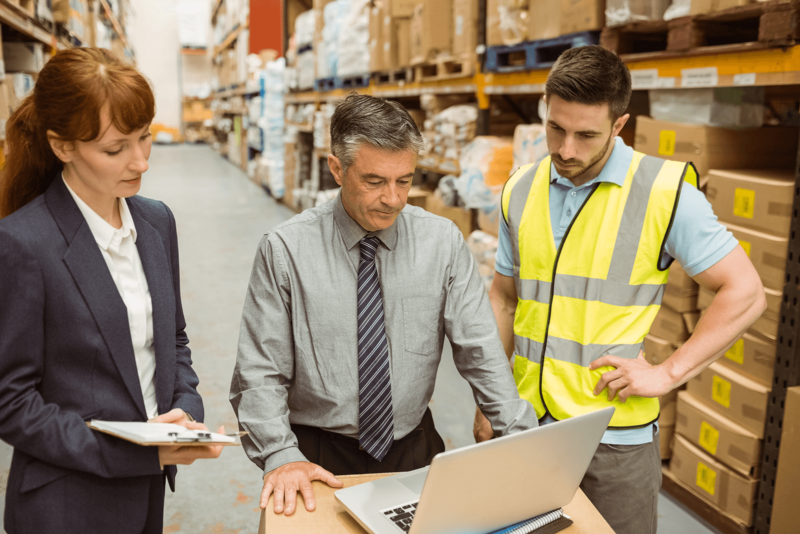 distribution merchants in a warehouse looking at a laptop