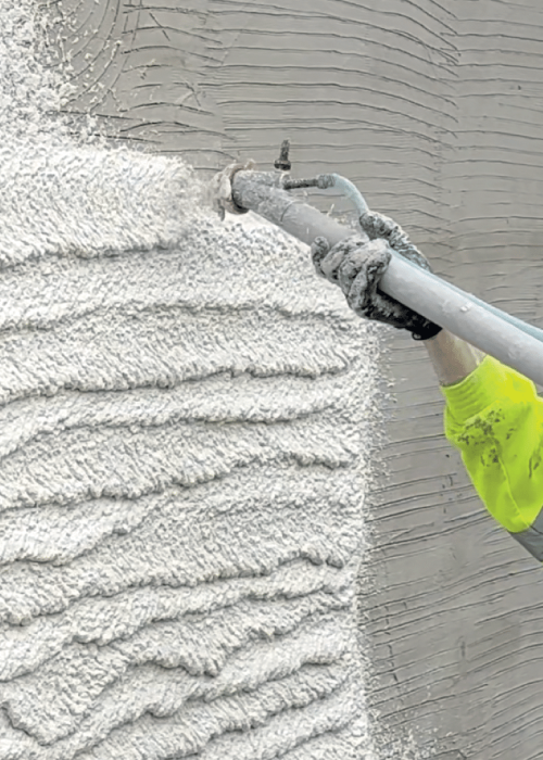 Machine spraying white render onto a wall
