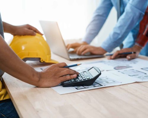 Contractors using a calculator on a desk