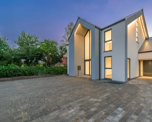 A modern house with external wall insulation (EWI) in the evening, with exterior lights