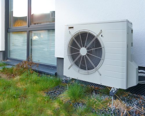 A heat pump on the outside of a rendered home with external wall insulation