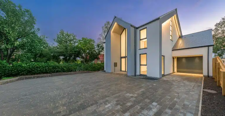 A modern house with external wall insulation (EWI) in the evening, with exterior lights